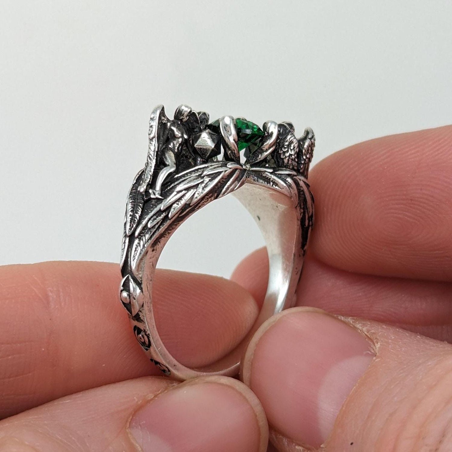 Sterling siler DND D&D engagement ring with 2 angels sculptures with wings emerald gemstone and dnd character art for ttrpg fans.